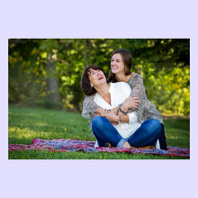 Load image into Gallery viewer, Mother and daughter sitting on a blanket in a park, hugging and smiling.
