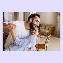 Load image into Gallery viewer, Man and woman dancing in a living room with a couch and chair in the background. Both are laughing.
